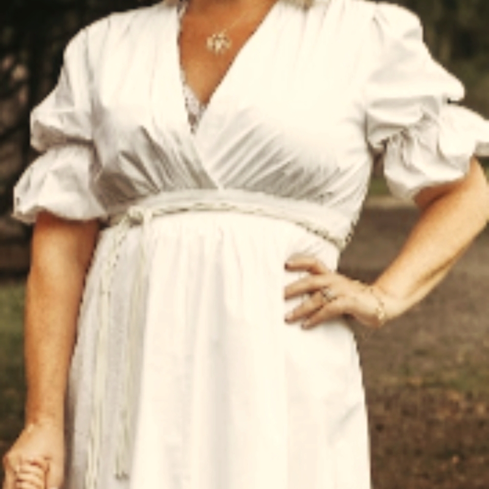 White long dress with braided belt and puffy sleeves.